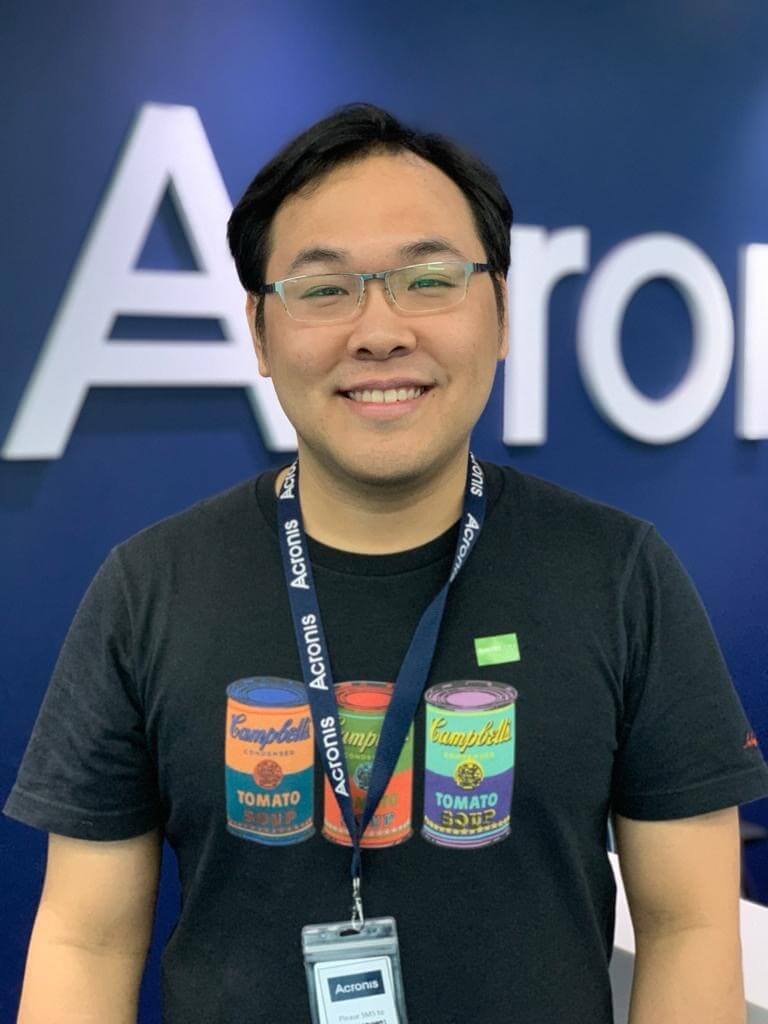 Ho Shuyuan smiling and standing in front of blue backdrop