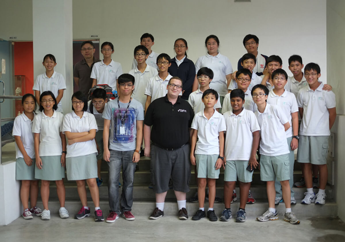 Students pose for a picture standing on a flight of stairs with their instructors