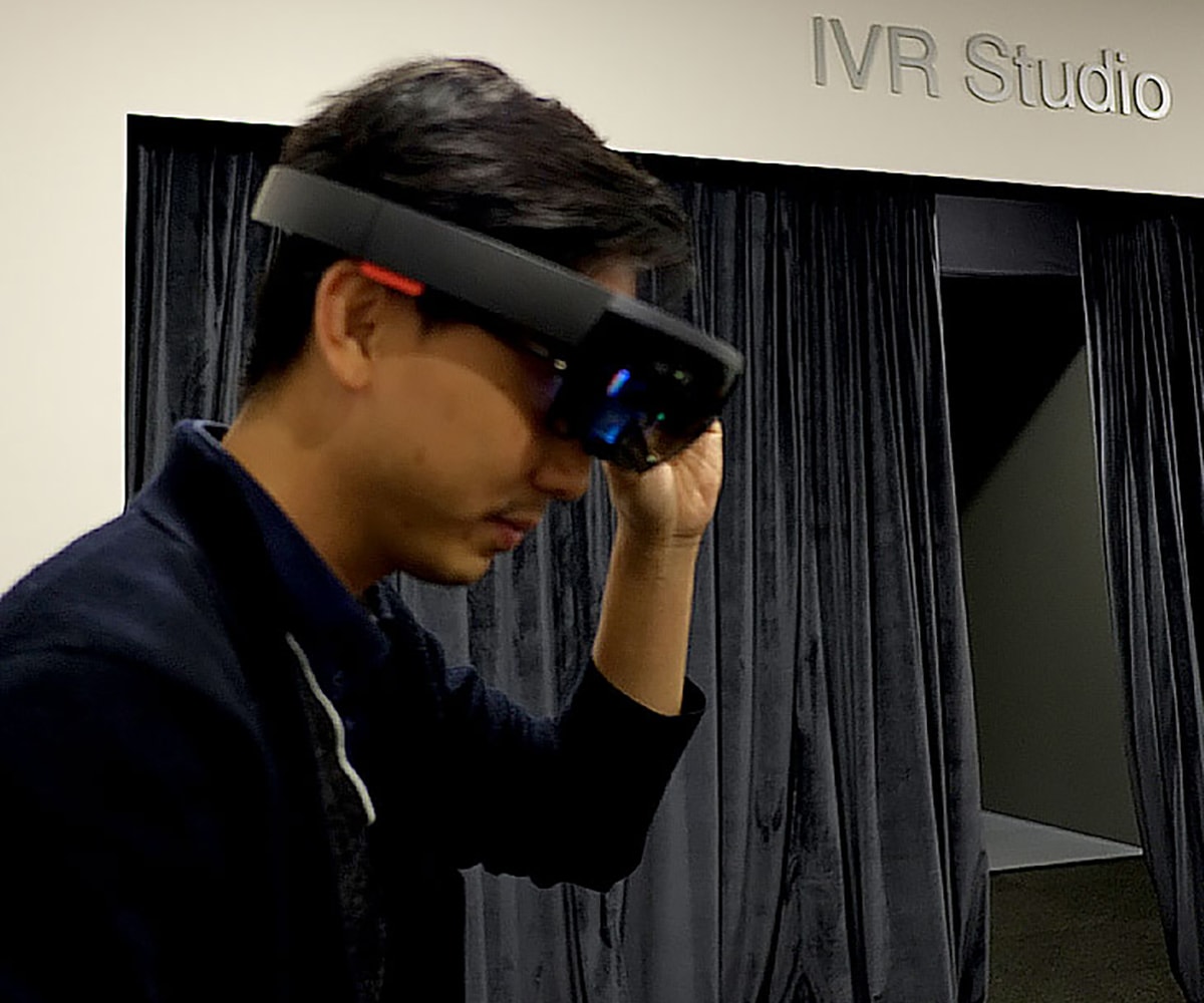 DigiPen (Singapore) alumnus wearing a virtual reality headset in front of a sign that says IVR Studio