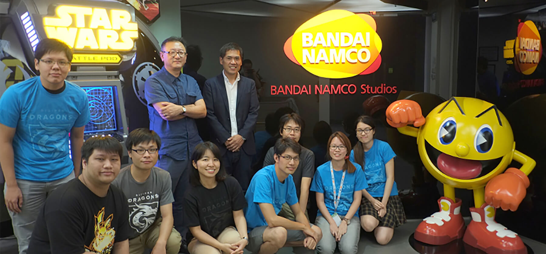 Students from DigiPen stand in the Bandai Namco Studios lobby next to a large, spherical Pac-Man model