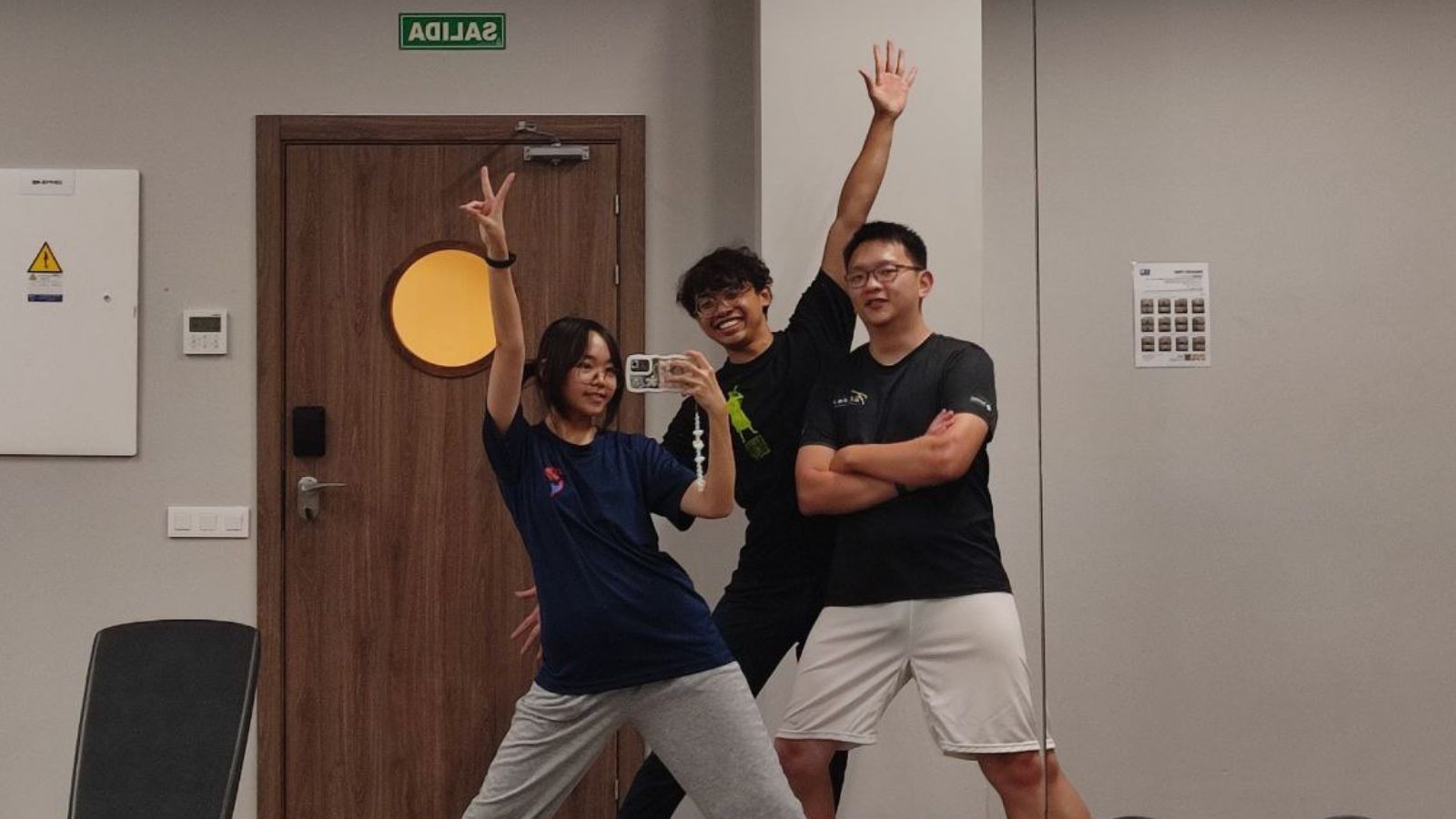 Three students pose together in a gym