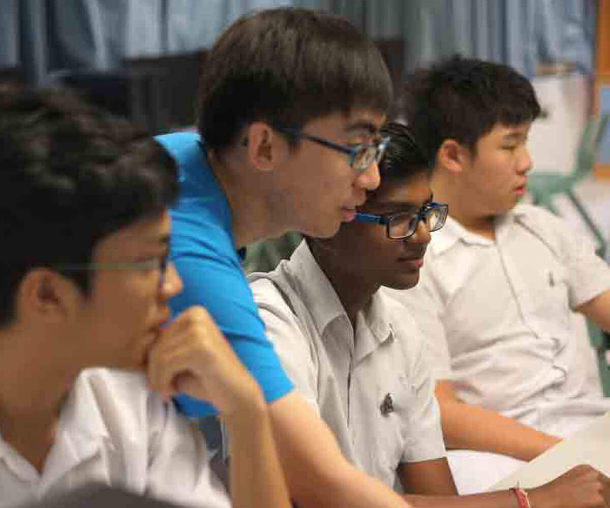 An instructor leans over the shoulder of a student sitting at a desk