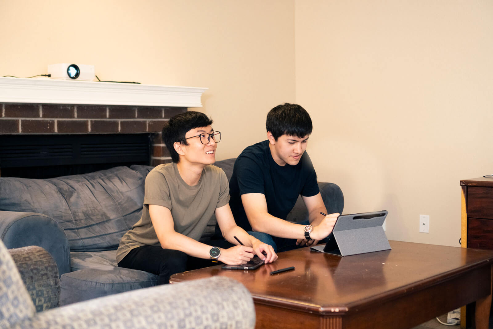 Two students sit together on a couch in a student apartment.