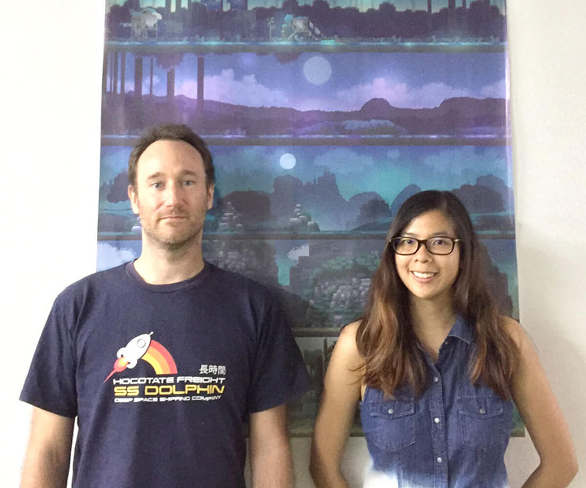 James Barnard and Cindy Lee stand in front a vertical game art tapestry