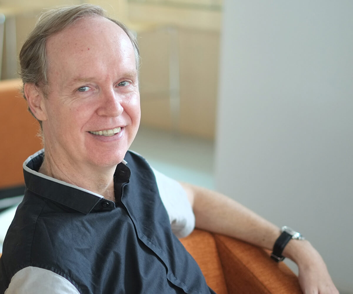 Department Chair of Game Software Design and Production, Joe McGinn, poses for a photo sitting on an orange chair