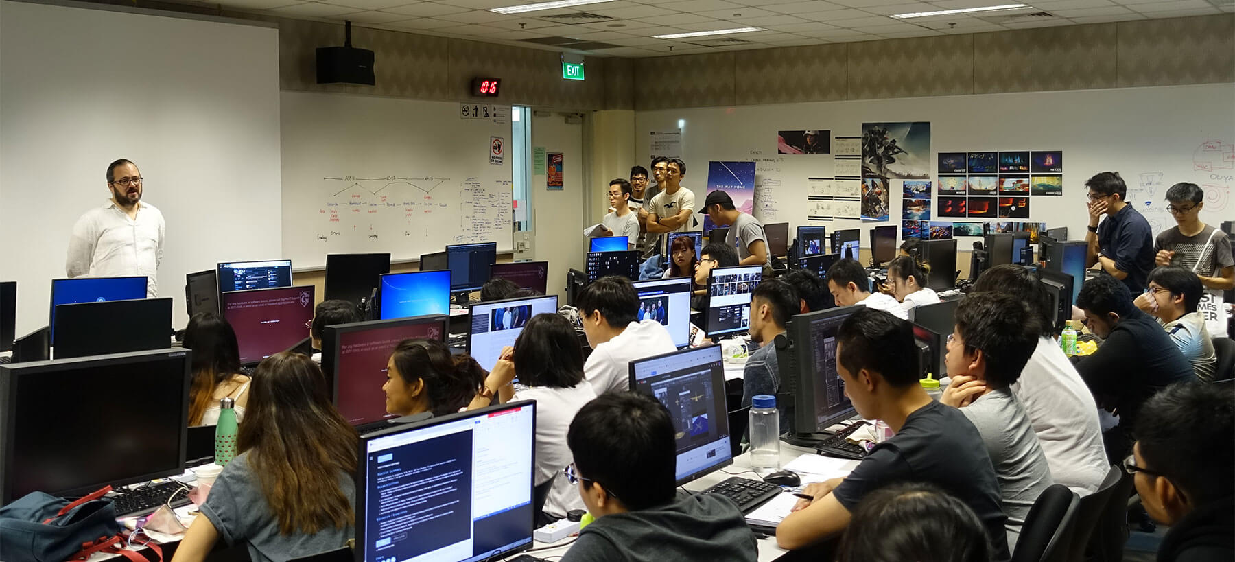 Ken Huff from Lucasfilm Animation Company Singapore stands in front of computer lab, giving a lecture presentation to a group of students.