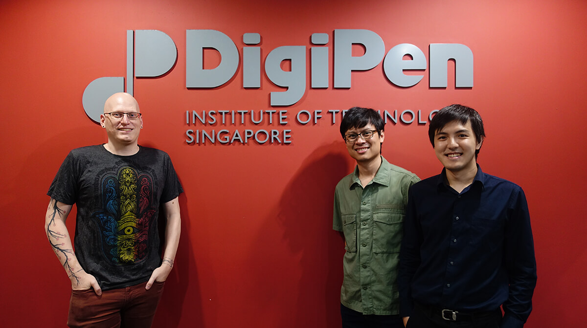 Kevin Prior, Howard Sin, and Gerald Wong stand in front of a red wall with the DigiPen Institute of Technology Singapore logo