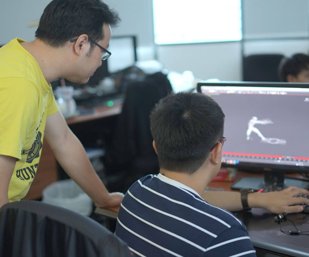Tyler Projects' CEO Leonard Lin observes a monitor over the shoulder of DigiPen graduate Lauri Gui