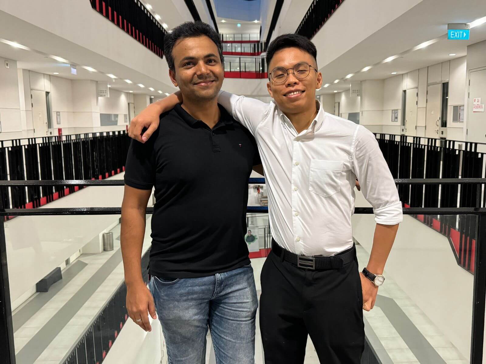 Two male graduate students standing in a university corridor.