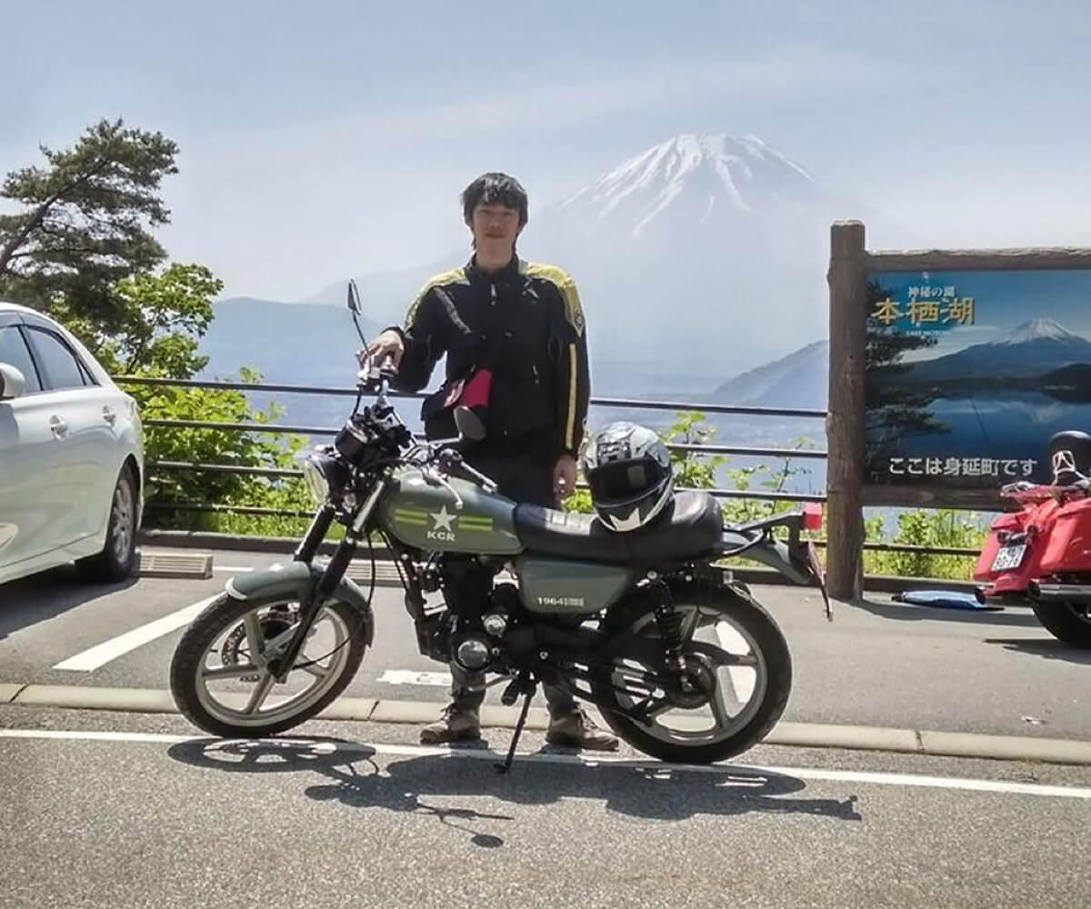 DigiPen (Singapore) alumnus Max Chew poses with a motorcycle, with a mountain in the background