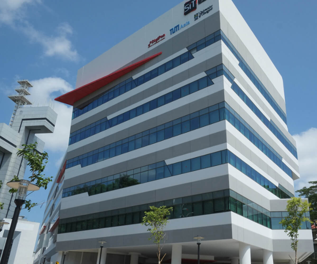 Modern, six-story building with red, white, and gray accents. Several company logos adorn the top right corner.