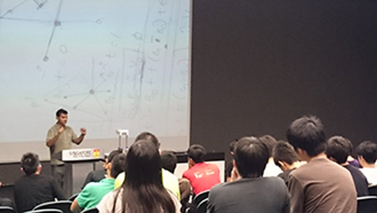 Prasanna Ghali stands in front of a projection screen addressing students in the audience