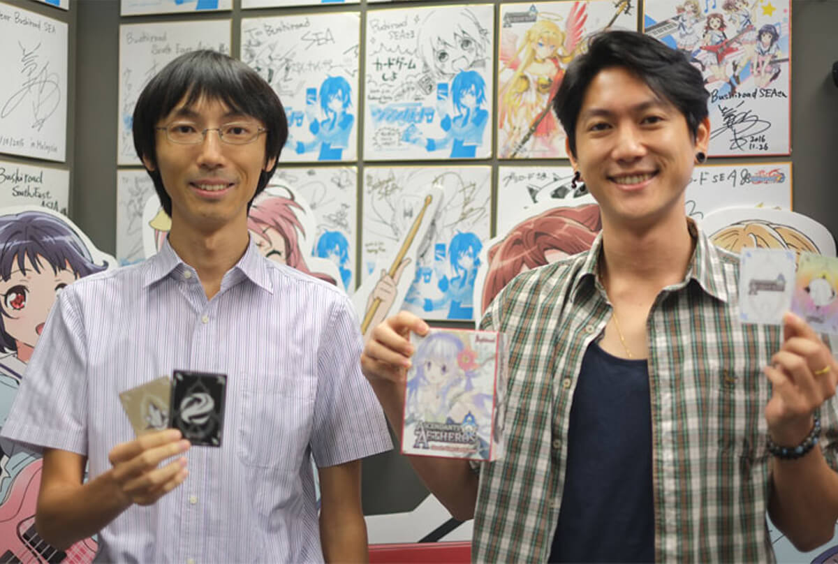 Graduate Rudy Ng and Shunichi Taira pose for a photo while holding cards from the Ascendants of Aetheros game