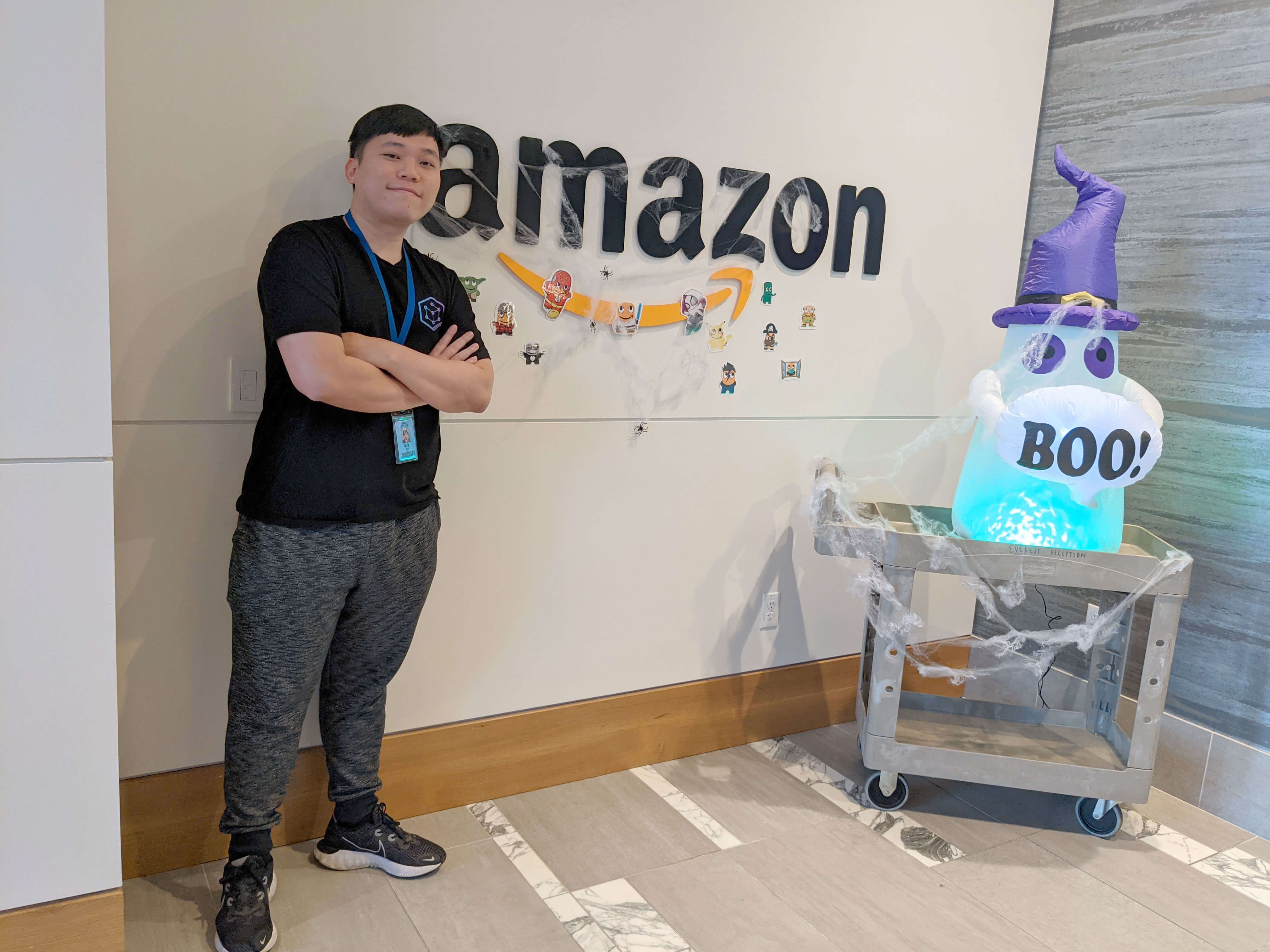 DigiPen alumni Thin Bing Zong stands next to Amazon corporate logo sign