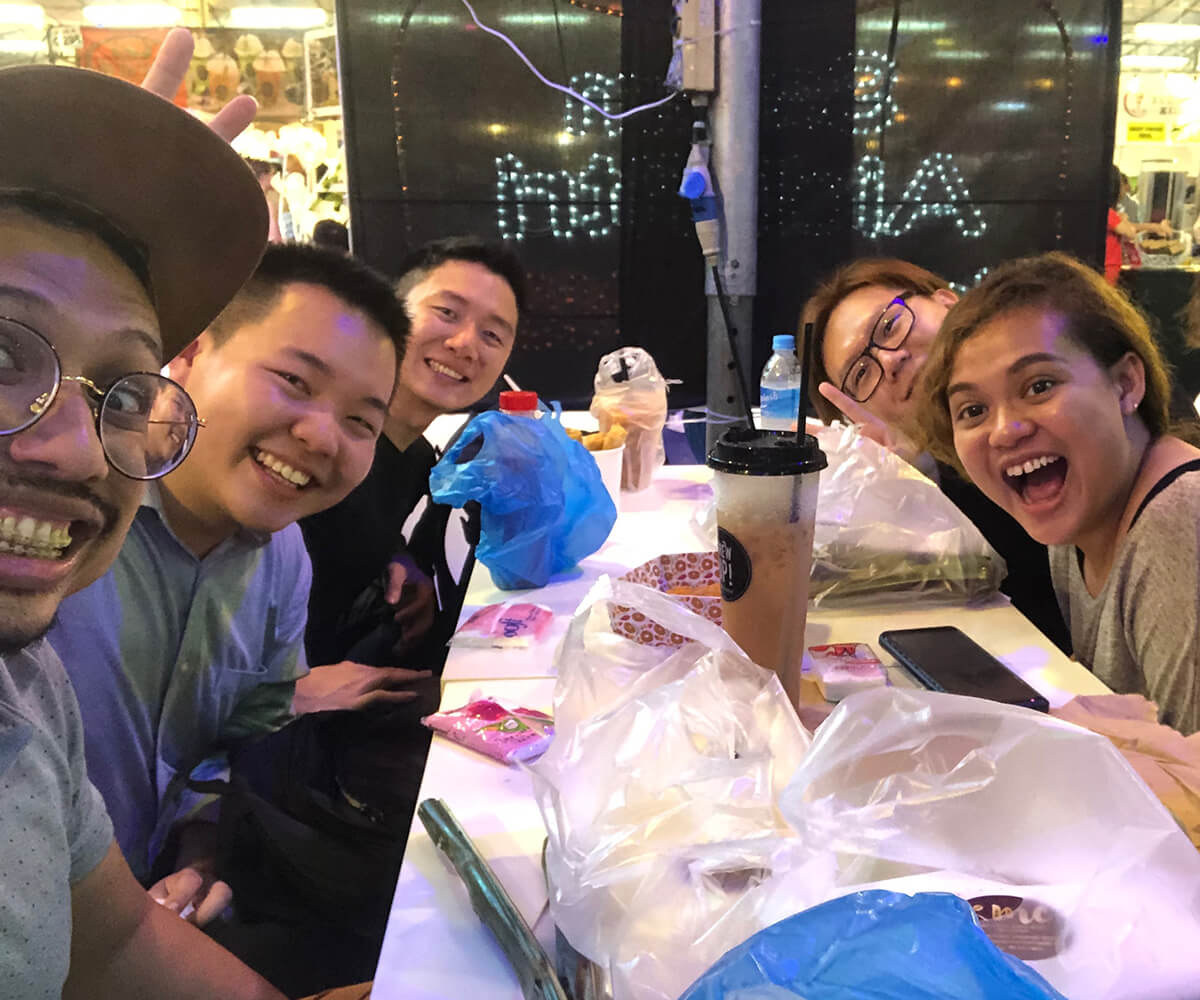 Five members of the new alumni committee smile at the camera while sitting around a restaurant table.