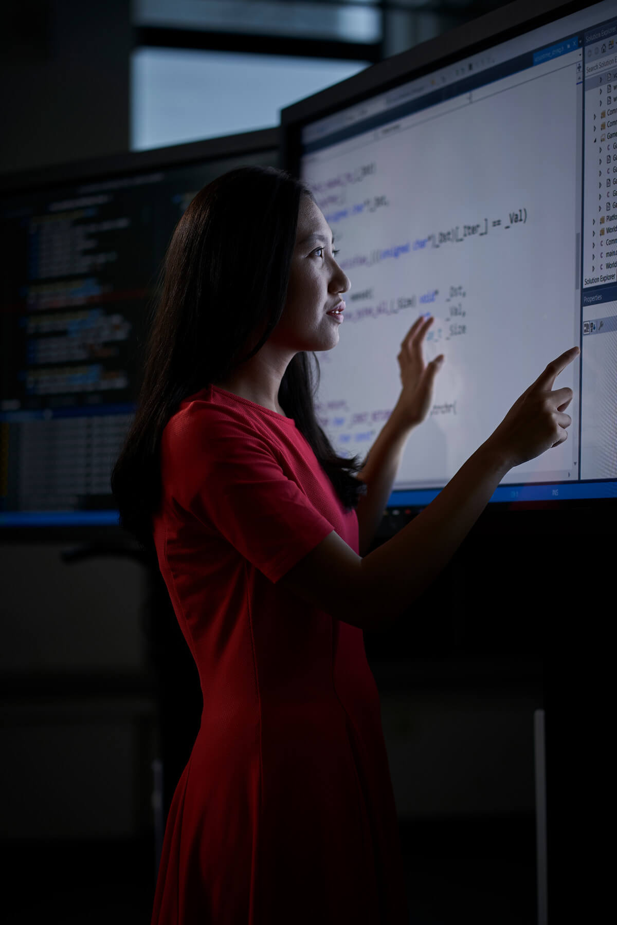 Female student standing and manipulating large touch screen mounted on wall