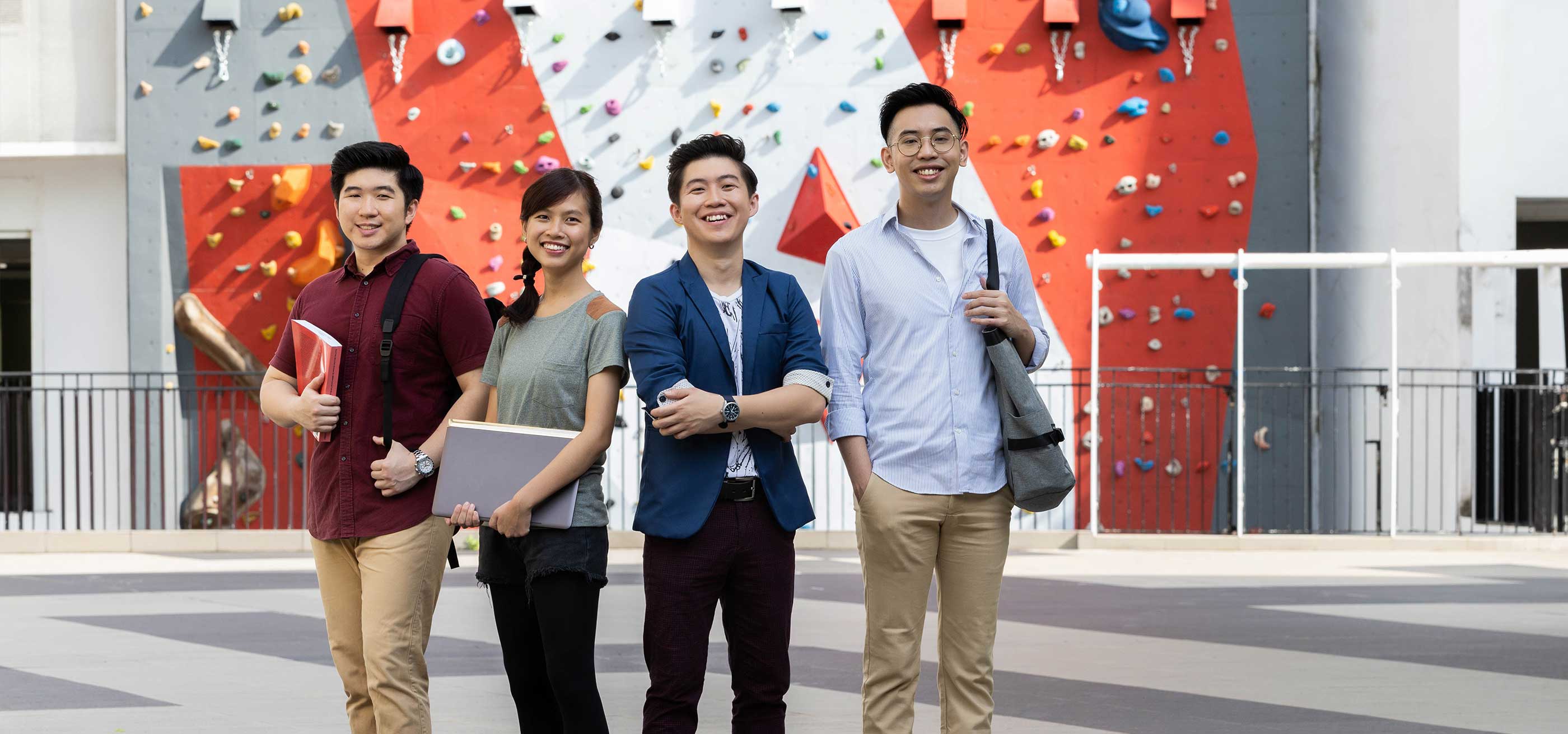 A group of students gathered in front of a stylized climbing wall.