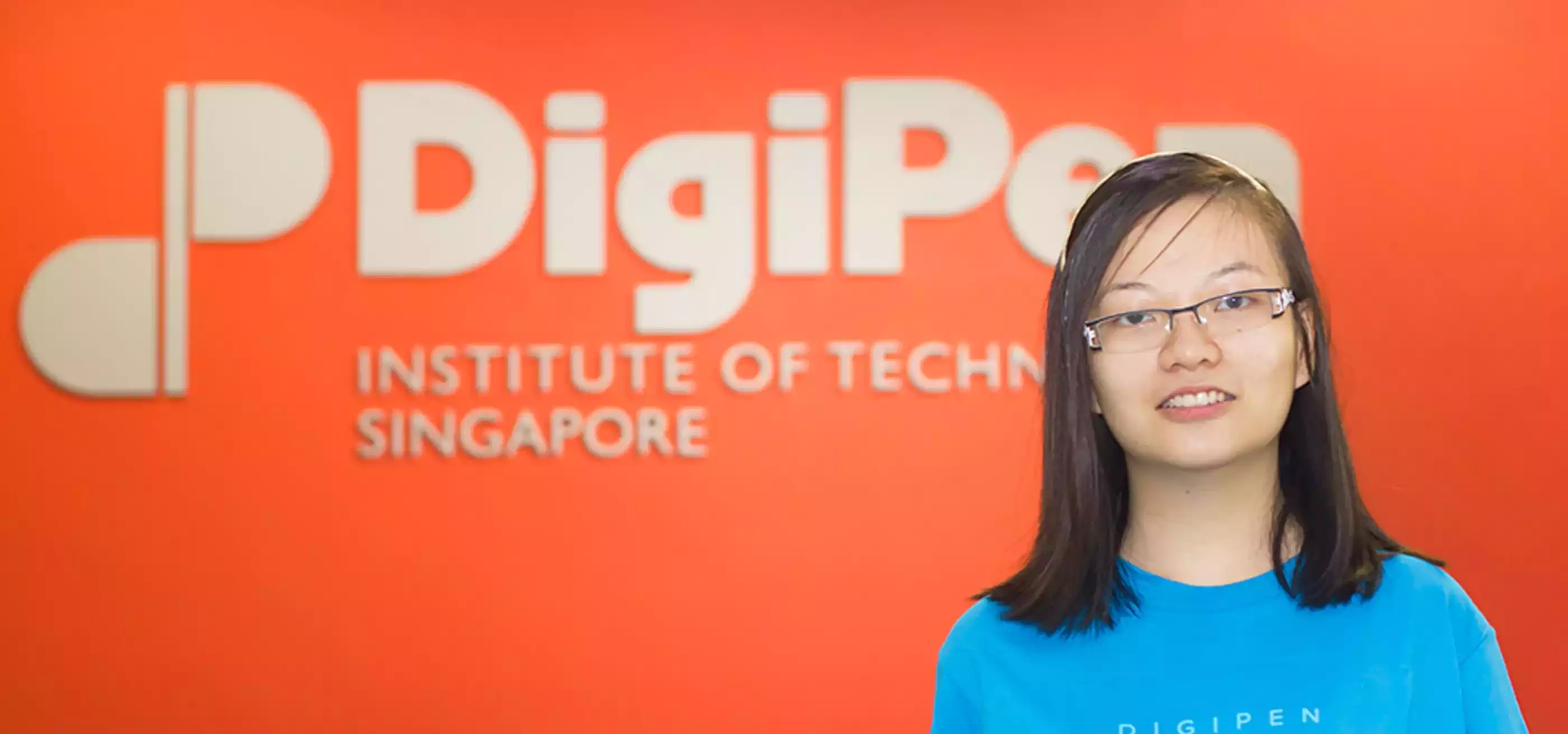 Alumna Chua Fen Ru Jurene posing for a photo in neon blue DigiPen Dragons t-shirt