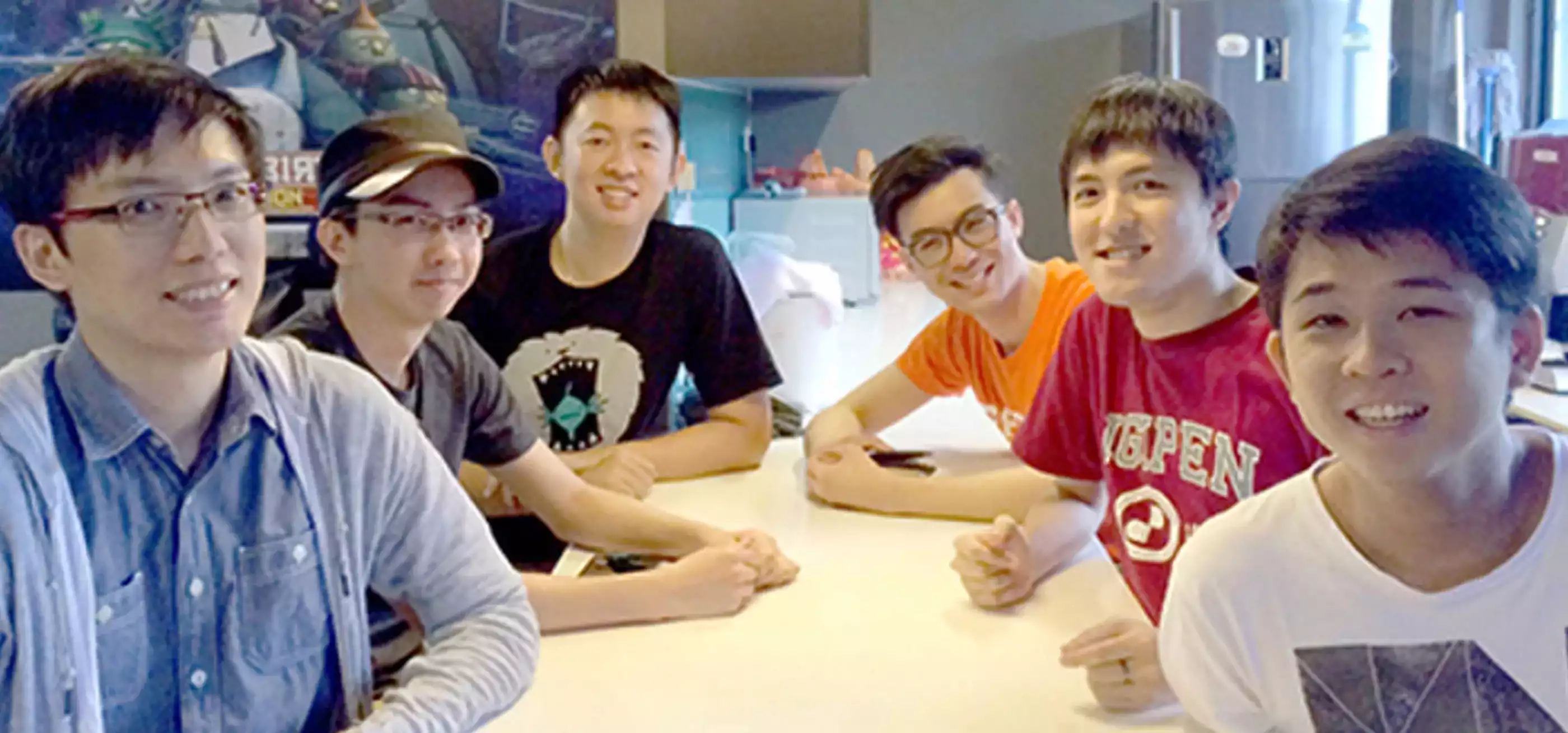 Six DigiPen alumni pose for a photo sitting at a table