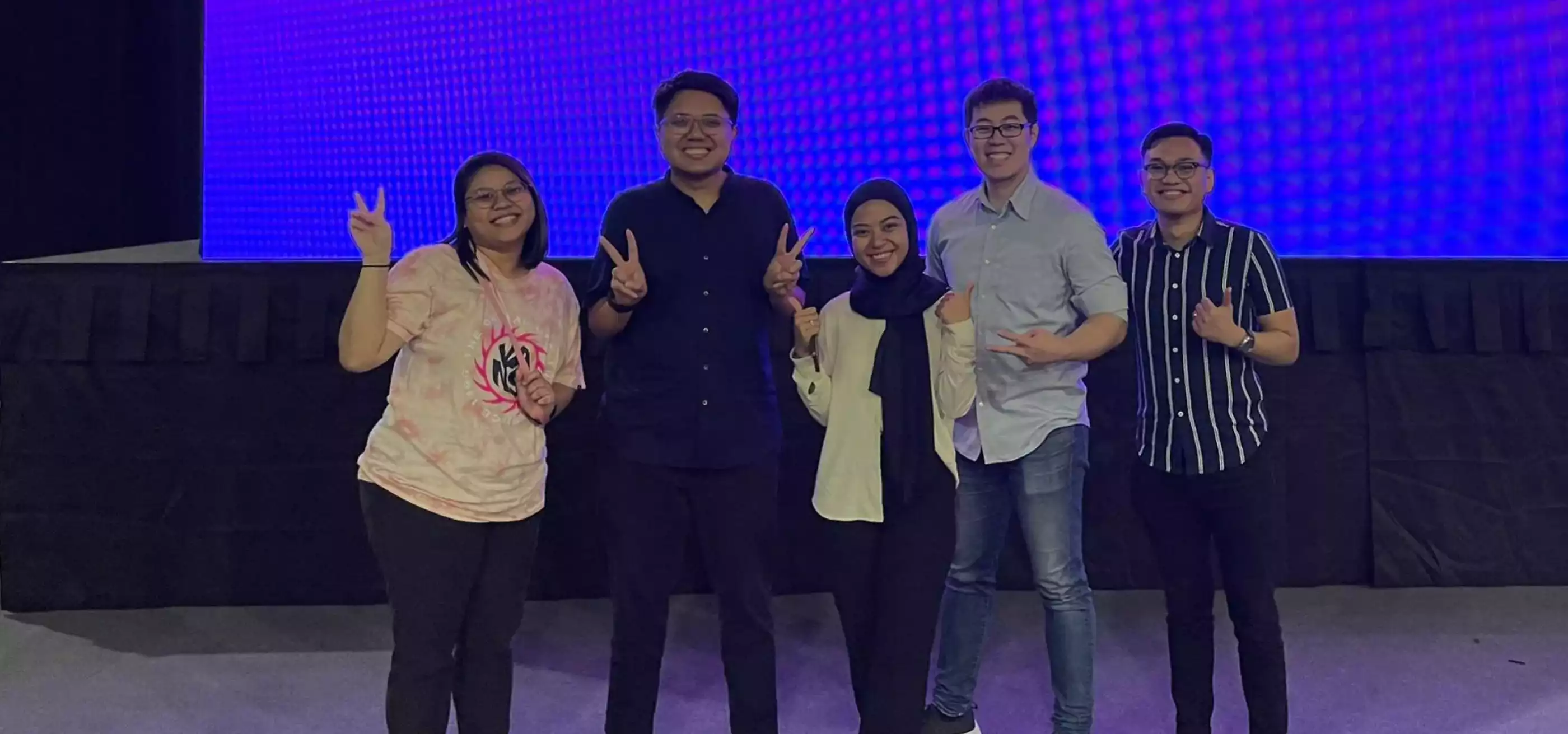Abdul Aziz poses with 4 other people in front of a Synapxe logo.