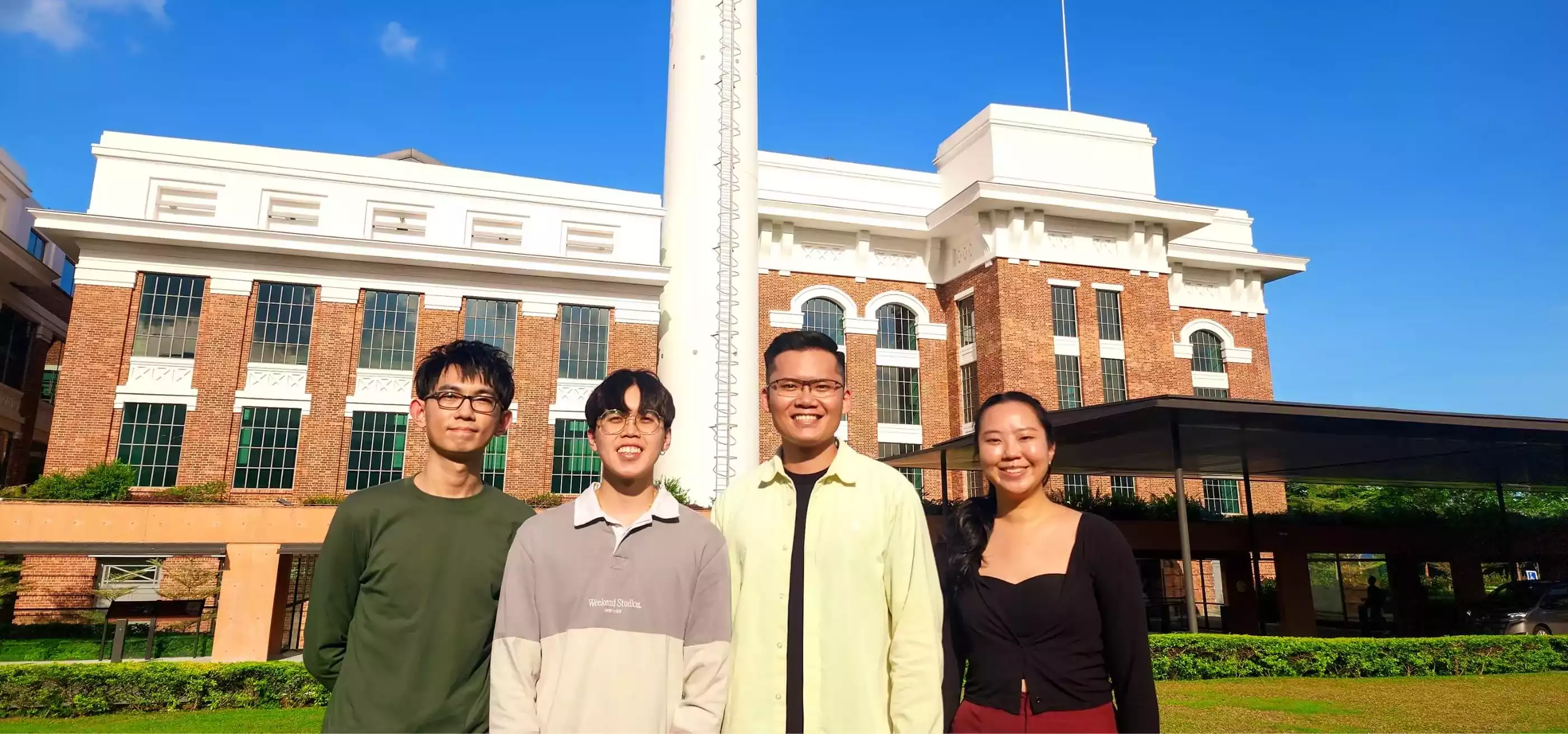 Four individuals standing outdoors in front of a building